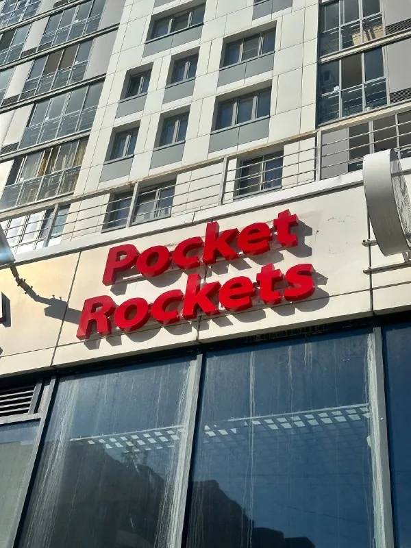 Красная вывеска Pocket Rockets на фасаде над входом